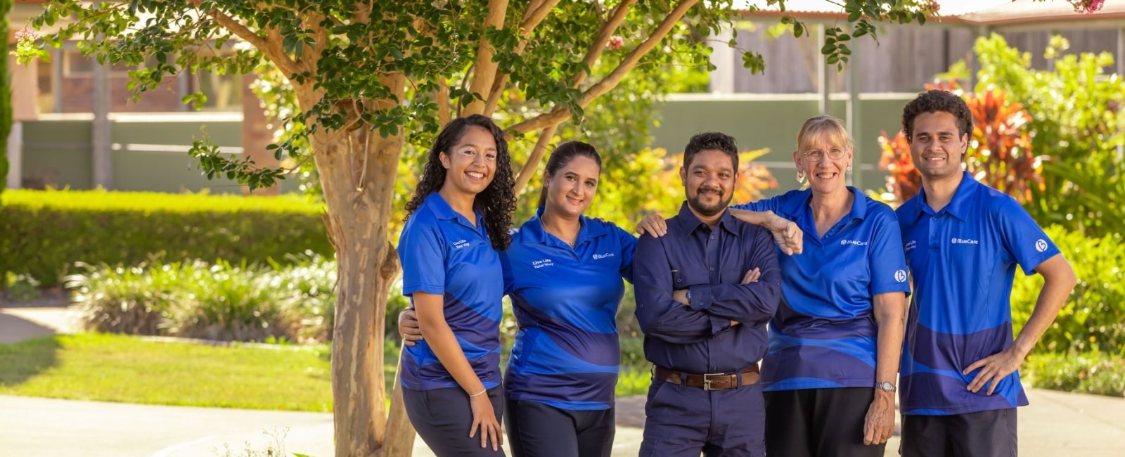 Working with us BlueCare team standing under tree